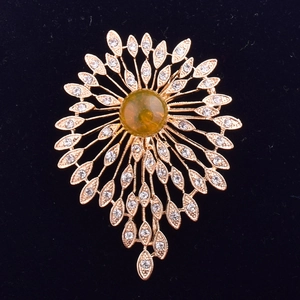 Detailed macro view of the gold sunburst brooch with crystal rhinestones and amber center