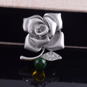 Elegant matte silver rose brooch with sparkling rhinestones and a green gemstone bead