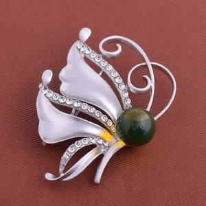 Détail d'une broche papillon argentée avec ailes blanches et cristaux brillants