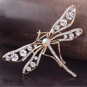 Gros plan d'une broche libellule en or rose avec cristaux blancs étincelants et diamant AB