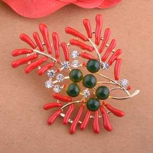 Détail de la broche corail avec branches rouges, perles vertes et cristaux étincelants