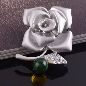 Macro shot of rose flower brooch with silver petals, green bead and pavé crystals
