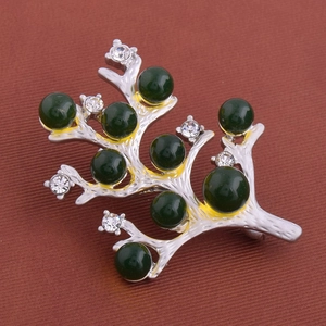 Détail de la broche branche argentée avec perles vert foncé et cristaux brillants