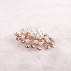 Détail d'une broche en perles avec strass sur base or rose sur fausse fourrure blanche