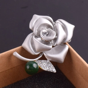 Macro detail of elegant silver rose brooch with green gemstone and sparkling rhinestones