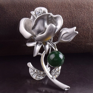 Détail macro d'une broche rose argentée avec pétales mats et cristal central brillant