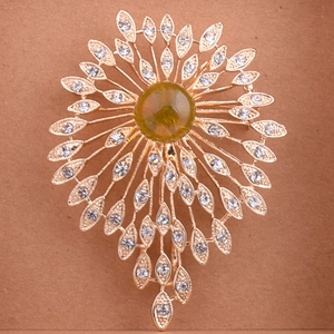 Detailed close-up of a vintage sun flower brooch with green stone and white rhinestones