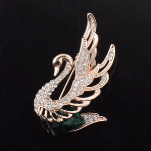 Vue détaillée de la broche cygne dorée rose sertie de cristaux et d'une pierre verte