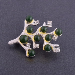 Vue détaillée d'une broche branche argentée avec neuf perles vertes et petits cristaux