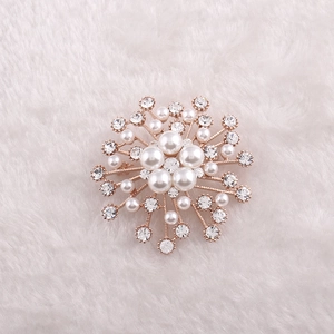 Détail d'une broche flocon de neige en or rose avec perles et cristaux sur fourrure
