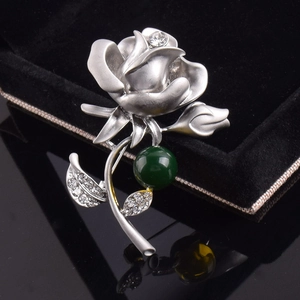 Gros plan détaillé d'une broche fleur argentée avec perle verte et strass brillants
