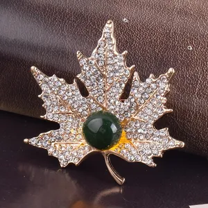 Détail de la broche en forme de feuille d'érable avec cristaux et pierre verte