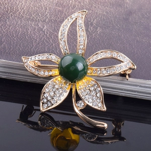 Eleganter goldener Blumenanstecker mit weißen Strasssteinen und grüner Perle