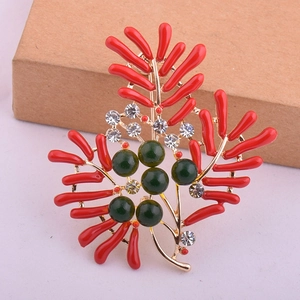 Détail d'une broche corail rouge avec des perles vertes et strass scintillants