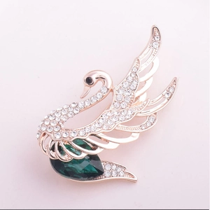 Élégante broche cygne dorée sertie de cristaux blancs et d'une pierre goutte vert émeraude