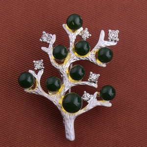 Détail de la broche branche argentée avec perles d'ambre vert et cristaux brillants