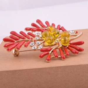 Vue détaillée d'une broche corail dorée avec émail rouge et perles jaunes