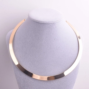 Detailed view of a sleek golden metallic choker necklace on a grey neck display stand