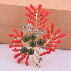Vue macro détaillée de la broche en corail avec émail rouge, métal doré et perles vertes