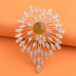 Golden crystal pearl brooch with amber center stone and white rhinestones on orange background