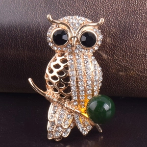 Sparkling owl brooch with gold plating, clear crystals, and a large deep green bead