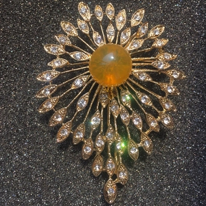 Exquisite golden sunburst brooch with amber resin center and shimmering crystal petals