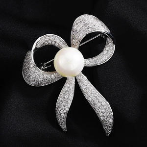 Funkelnde silberne Schleifenbrosche mit Zirkonia und großer Perle auf schwarzem Satin
