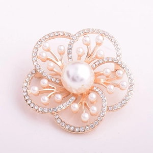 Détail d'une broche florale dorée ornée de perles blanches et de strass brillants de luxe