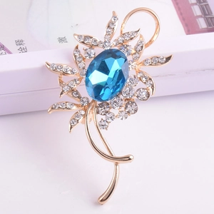 Vue détaillée d'une broche fleur dorée avec cristal bleu et strass brillants incrustés