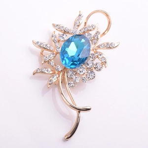 Vue détaillée d'une broche fleur dorée avec pierre bleue ovale et cristaux étincelants