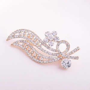 Elegant gold leaf brooch with floral motif and sparkling rhinestones on plain background