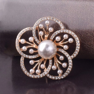 Vue détaillée d'une broche fleur dorée avec perle centrale et pétales en strass
