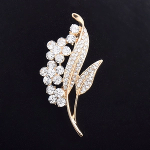 Close-up of golden crystal flower brooch with detailed clear rhinestones on black velvet