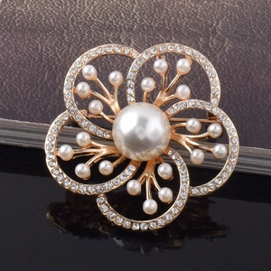 Détail macro d'une broche fleur en strass avec perle centrale et alliage doré chic