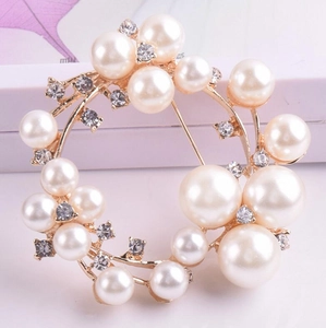 Detalle del broche de corona de perlas elegantes con cristales y acabado dorado
