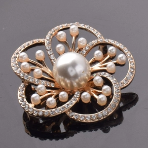 Détail de la broche fleur dorée avec perle blanche centrale et pétales en cristal