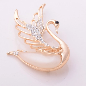 Detailed view of the gold swan brooch with sparkling crystals and opal-like stones