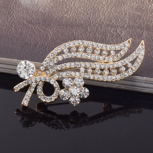 Macro shot of gold-plated leaf brooch showing intricate wavy bands and sparkling rhinestones
