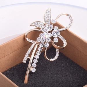 Broche fleur dorée avec cristaux blancs sur un écrin de luxe en velours noir
