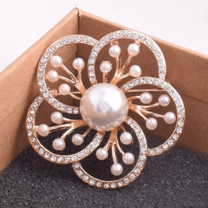 Vue détaillée de la broche fleur avec perle centrale sur un coussin de bijoux noir
