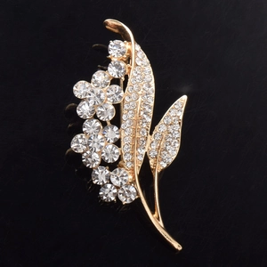 Close-up of golden flower brooch with sparkling crystal rhinestones on black surface