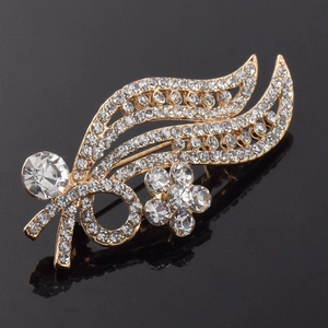 Macro detail of leaf-shaped rhinestone brooch featuring elegant gold alloy and large round gem