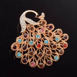 Détail d'une broche paon dorée ornée de cristaux multicolores sur un fond noir