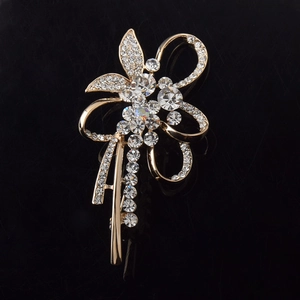 Détail macro d'une élégante broche fleur dorée avec chaînes en strass sur fond noir brillant