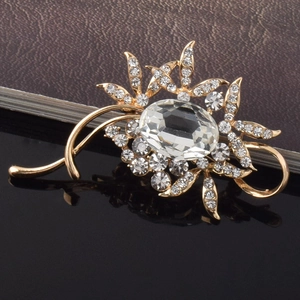 Vue détaillée d'une broche fleur dorée avec gemme ovale et strass brillants sur noir