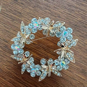 Detail of a golden wreath brooch with blue crystals and dragonflies on wood