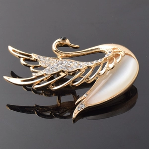 Detailed macro shot of golden swan brooch featuring white opal and sparkling rhinestones