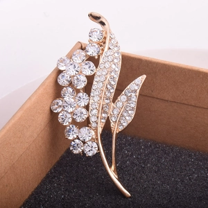 Detailed close-up of a golden flower brooch with sparkling crystals on black foam padding