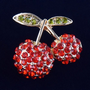 Close-up of cherry brooch with red and green rhinestones on gold alloy frame
