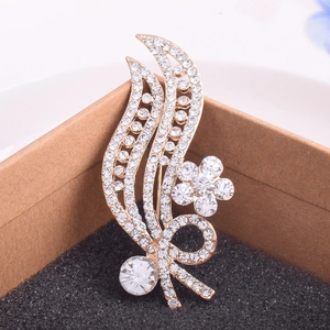Close-up of golden leaf brooch with sparkling white rhinestones on black cushion